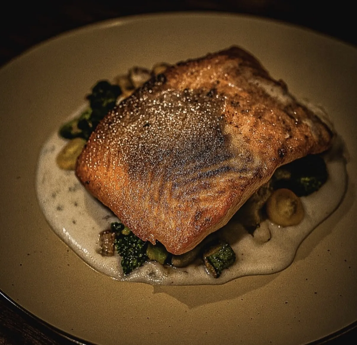 Salmón con piel dorada sobre crema y vegetales